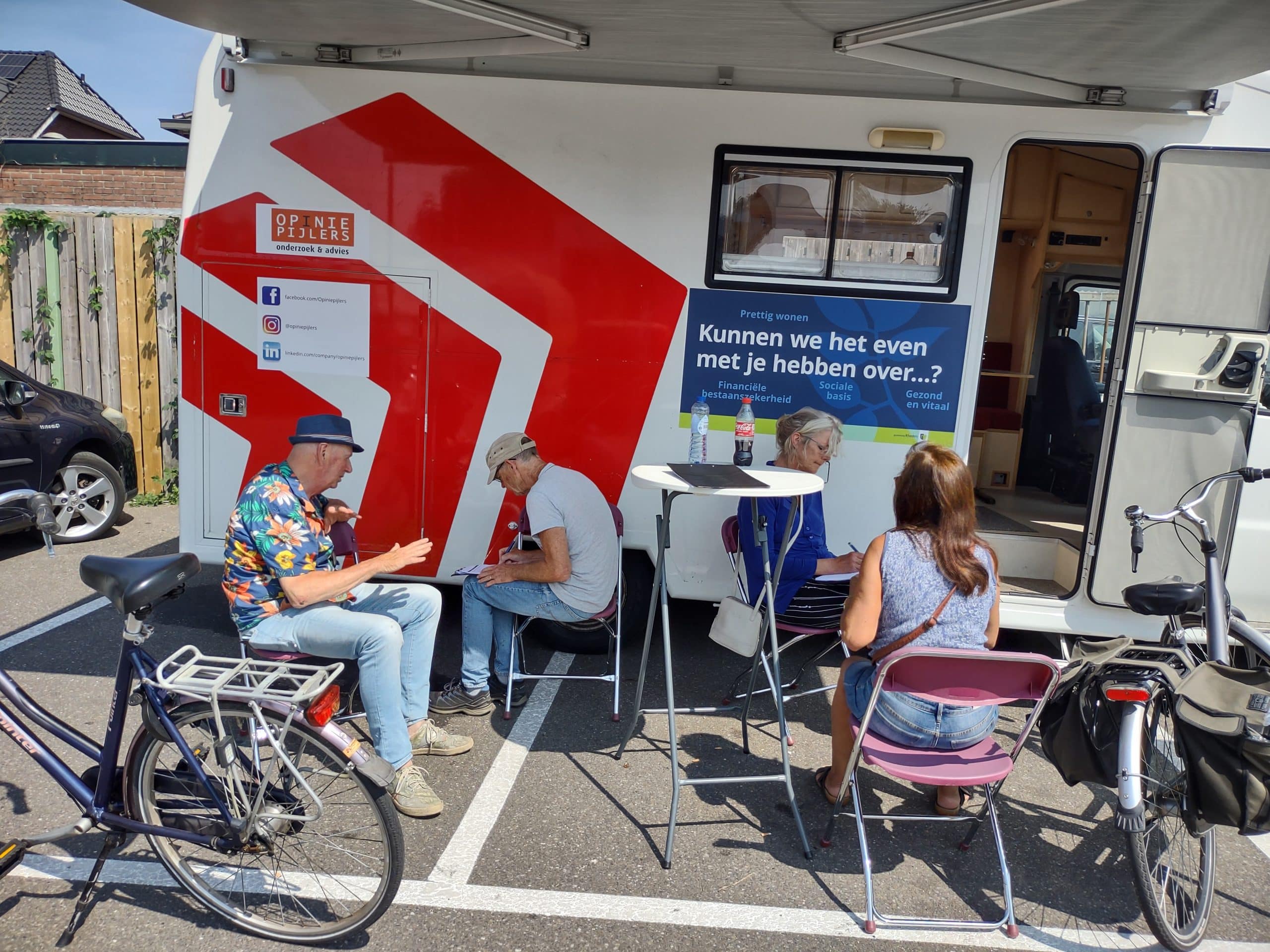 Afbeelding van de Opiniepijlers gespreksbus, met onze interviewers actief in gesprek met inwoners